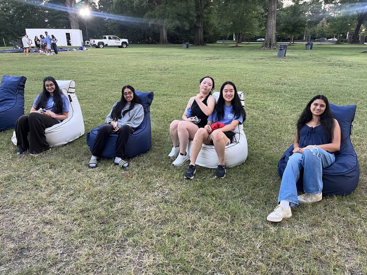 A full crowd of students on bean bag chairs at a night-time campus screening