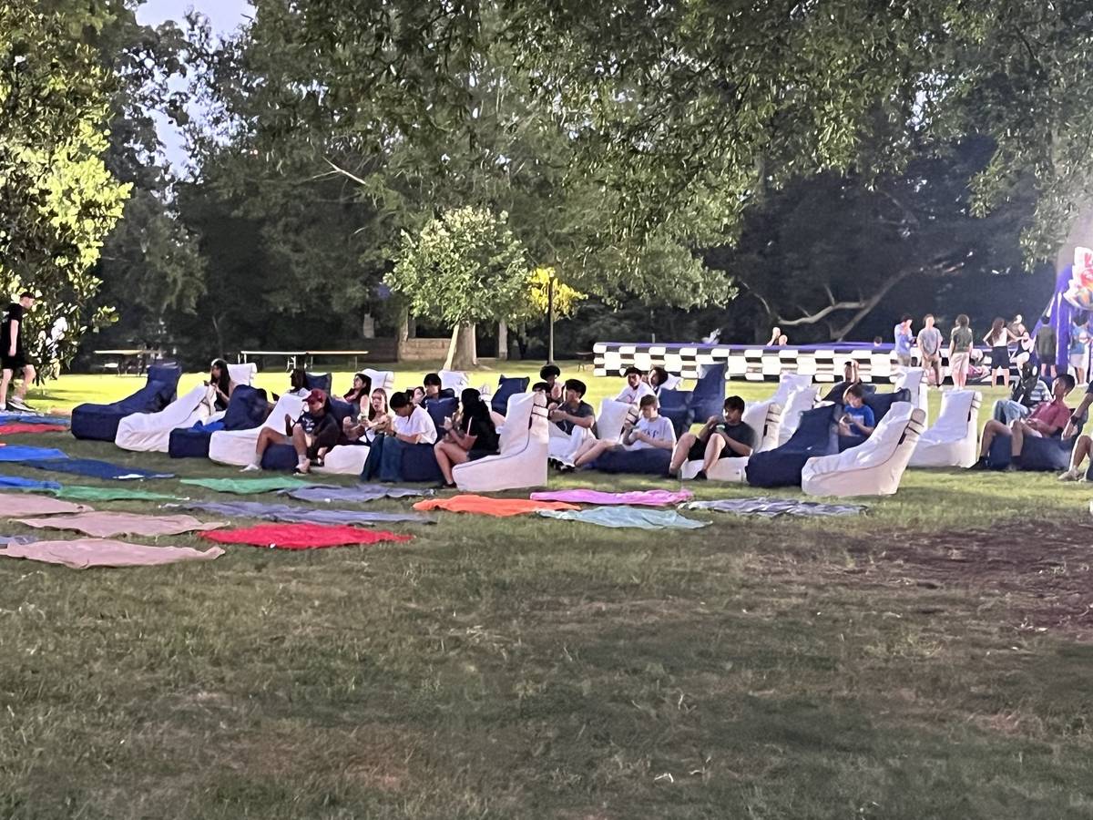 Guests on bean bag chairs and blankets at an evening gathering on a lawn