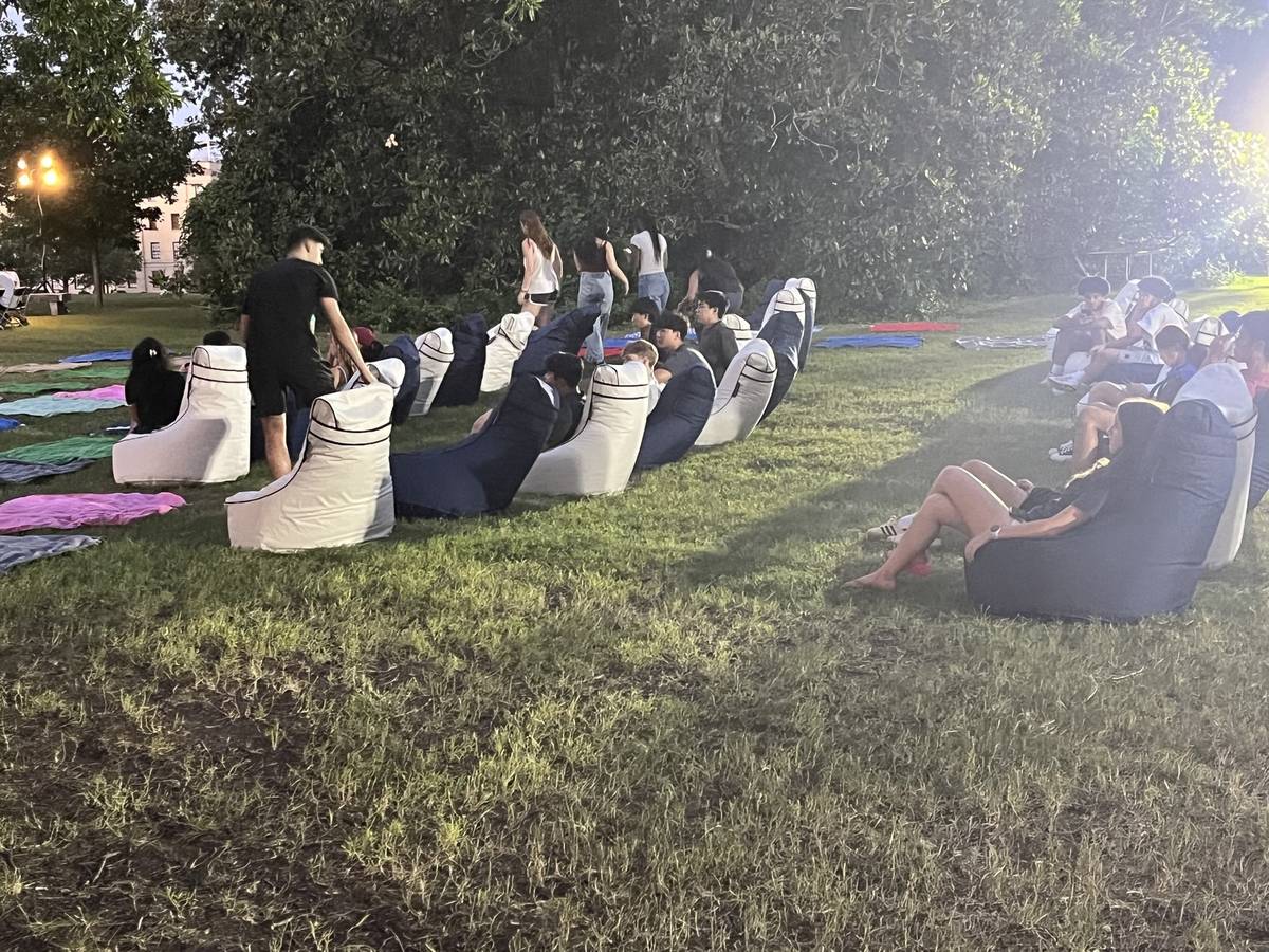 The film playing on an outdoor screen with guests seated on bean bag chairs
